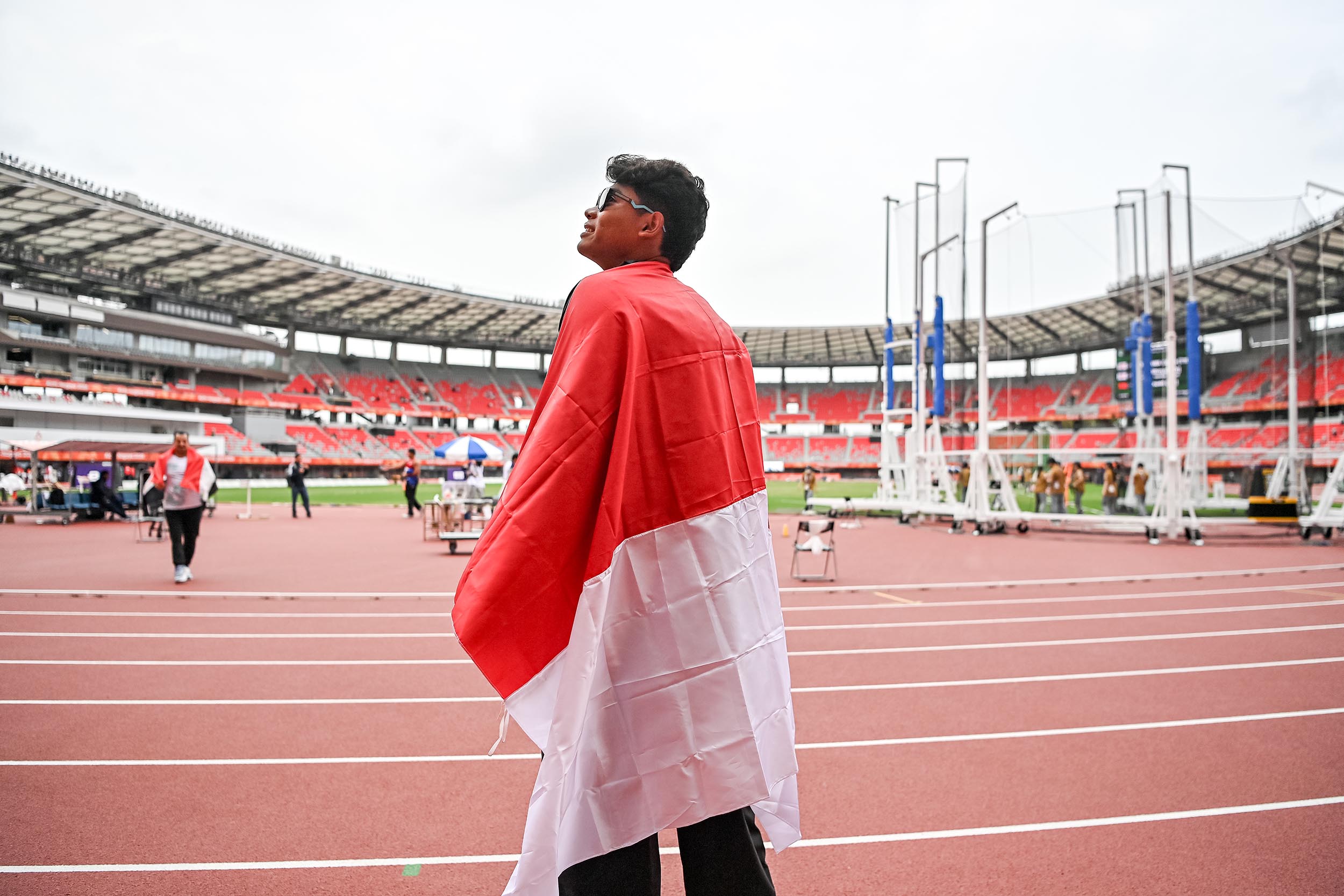 Atlet lempar cakram Indonesia I Kadek Dwi Purwana Yasa membawa bendera usai menang pada final atletik lempar cakram putra F57  di Stadion Paloma Mizuho, Nagoya, Aichi, Jepang, Selasa (20/10/2026). Kadek berhasil meraih medali emas setelah berhasil mencatatkan lemparan terbaiknya sejauh sejauh 49,75 meter sekaligus memecahkan rekor dunia atas dirinya sendiri. NPC INDONESIA/Mohammad Ayudha